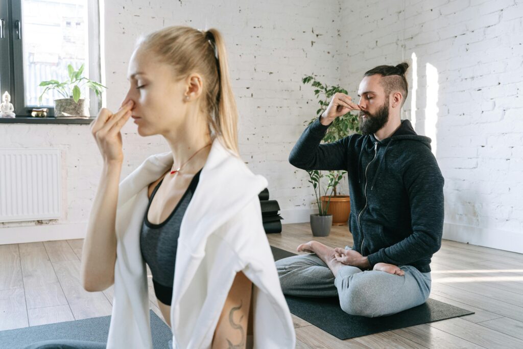 A man and woman practicing mindful yoga and breathing exercises in a serene indoor setting.